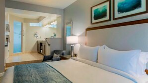 Una camera d'albergo con un letto grande, una scrivania, una sedia e un bagno visibile attraverso una porta aperta.