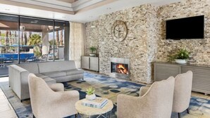 A modern living room with a stone wall, a fireplace, and a flat-screen TV.