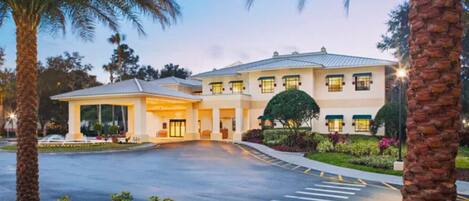 A hotel with a covered entrance, a parking lot, and landscaped gardens.