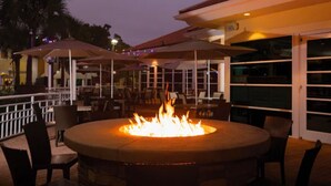 An outdoor seating area with a circular fire pit surrounded by chairs and tables. - Sheraton Vistana Resort (1BR) (Orlando)