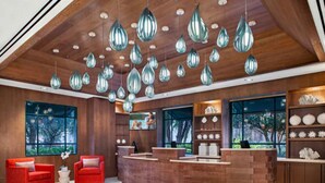 A modern reception area with a wooden reception desk, red chairs, and hanging pendant lights. - Sheraton Vistana Resort (1BR) (Orlando)