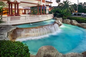 A pool with a waterfall feature, surrounded by rocks and greenery. - Sheraton Vistana Villages (2BR) (Orlando)