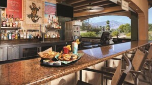 Un espace bar doté d’un comptoir en granit, de tabourets de bar, d’un barbecue et offrant une vue sur les montagnes.