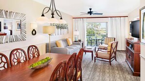 A hotel room with a dining area, a sofa, a TV, and a balcony with a view. - Sheraton PGA Vacation Resort (2BR) (Port St. Lucie)