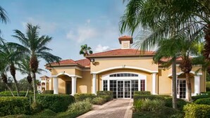 A large, two-story building with a symmetrical facade, a central entrance with a glass door, and a tiled roof. - Sheraton PGA Vacation Resort (2BR) (Port St. Lucie)