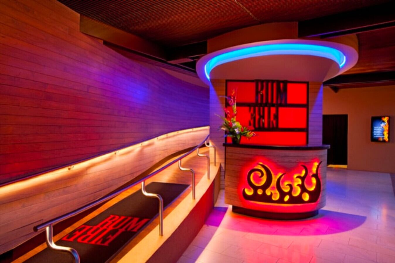 A reception area with a modern design, featuring a wooden bench and a counter with illuminated signage.