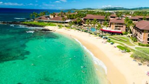 A beach resort with multiple overwater bungalows, a sandy beach, and clear turquoise waters. - Sheraton Kaua‘i Resort Villas (1BR) (Koloa)