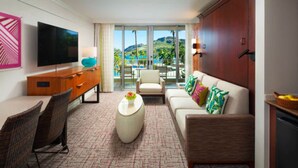 Une chambre d’hôtel dotée d’une grande télévision, d’un canapé, d’une table à manger et offrant une vue sur une piscine et des montagnes.