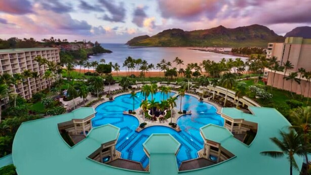 Un complexe hôtelier doté de plusieurs piscines, de palmiers et offrant une vue sur la plage.