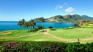 Un campo de golf con vistas al océano y montañas al fondo.
