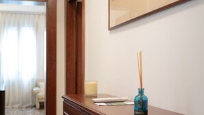 Habitación de hotel con tocador de madera, una obra de arte enmarcada en la pared, una vela y una botella azul con ramitas.