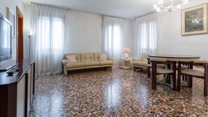 Una sala de estar con sofá, una mesa de centro, televisor y una mesa de comedor con sillas.