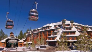 Une station de ski dotée d’un grand chalet, de remontées mécaniques et d’arbres couverts de neige.