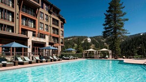 Un hôtel doté d’une piscine, de chaises longues et offrant une vue sur un paysage montagneux.