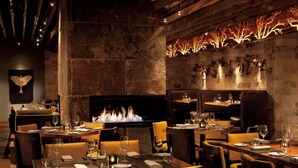Un restaurant avec un mur en pierre, une cheminée et des tables dressées pour le dîner.