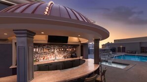 A rooftop bar with a pool, bar stools, and a large screen. - Marriott's Grand Chateau (Studio) (Las Vegas)