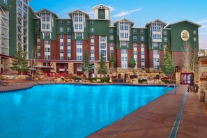 Un hotel con una amplia piscina exterior, edificios de varios pisos y fachada de piedra.