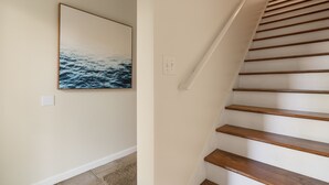 Una escalera con escalones de madera y un cuadro colgado en la pared que muestra el océano.