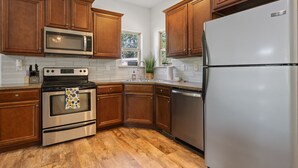 Una cocina con armarios de madera, electrodomésticos de acero inoxidable y piso de madera.