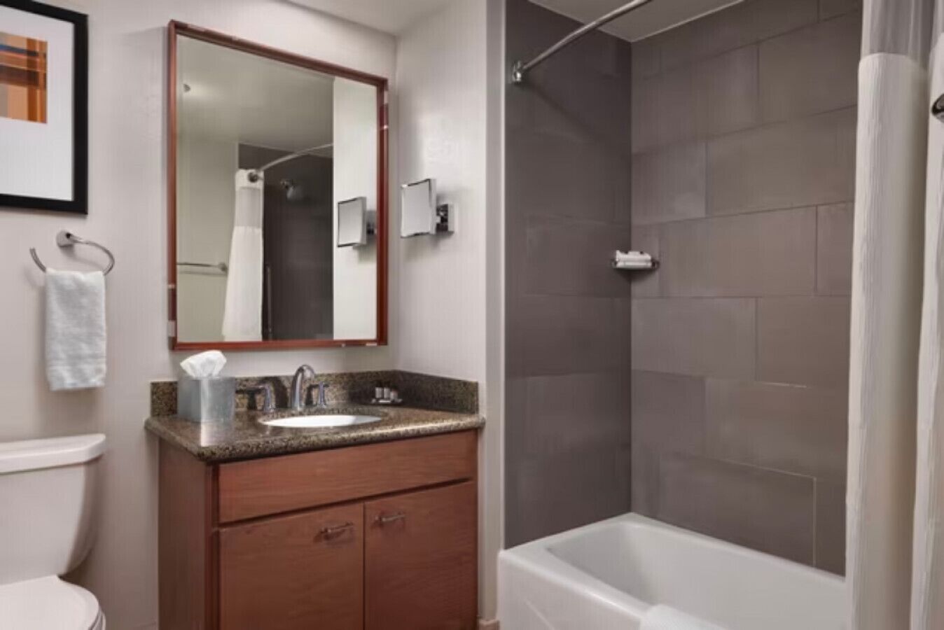 A bathroom with a sink, mirror, and shower.