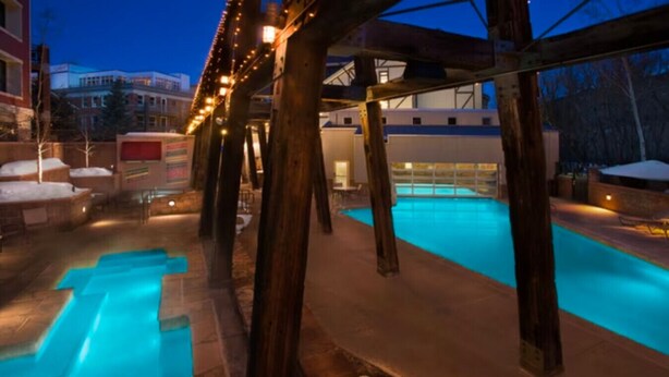 An indoor swimming pool with wooden beams, a stone floor, and a view of buildings in the background. - Marriott's Summit Watch (Studio) (Park City)
