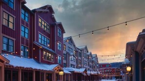 A snow-covered street lined with traditional wooden buildings, featuring large windows and a rustic architectural style. - Marriott's Summit Watch (1BR) (Park City)