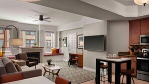 A modern living room with a sofa, coffee table, and a dining area with a table and chairs. There is a kitchen area with a microwave and stove. - Marriott's Summit Watch (1BR) (Park City)