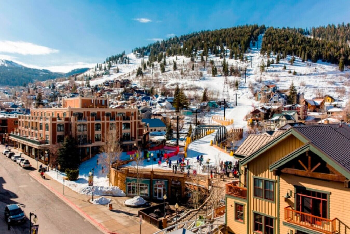 A town with buildings, a road, and a snowy mountain in the background.