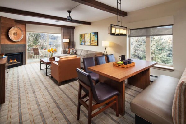 A spacious living area with a fireplace, a dining table with chairs, and a sofa.
