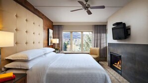 A hotel room with a large bed, a television mounted on the wall, a fireplace, and a ceiling fan. - Sheraton Mountain Vista Villas (2BR) (Avon)