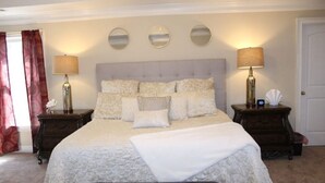 Une chambre à coucher bien aménagée, avec un grand lit, deux tables de chevet et trois miroirs fixés au mur.