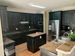 A modern kitchen with dark cabinets, stainless steel appliances, and a granite countertop.
