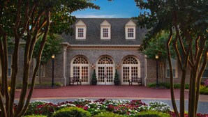 A building with a symmetrical facade, featuring a central entrance flanked by two arched windows and a set of double doors. - Marriott's Manor Club (2BR) (Williamsburg)