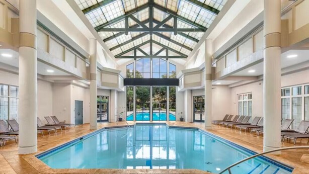 Ein Hallenbad mit hoher Decke und großen Fenstern.