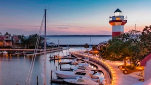 Ein Yachthafen mit angestaubten Booten, einem Leuchtturm und einer Uferpromenade mit Beleuchtung.