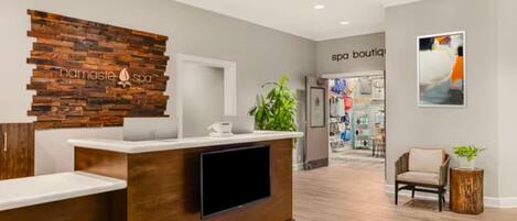 A reception area with a wooden reception desk, a flat-screen TV, and a wall-mounted sign that reads 'namaste spa'.