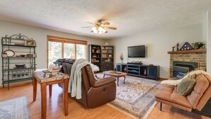 A living room with a fireplace, a television, a bookshelf, and a dining area. - Game Room & Deck: Serene Ava Countryside Home (Ava)