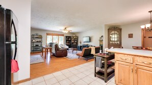 A spacious living area with a kitchen, wooden cabinets, a dining table, and a ceiling fan. - Game Room & Deck: Serene Ava Countryside Home (Ava)