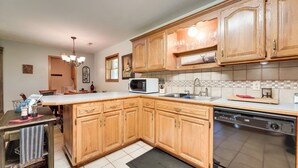 A kitchen with wooden cabinets, a microwave, a dishwasher, and a tiled backsplash. - Game Room & Deck: Serene Ava Countryside Home (Ava)