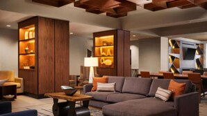 Una sala de estar moderna con un sofá seccional, estanterías de madera y un comedor con mesa y sillas.