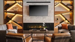 A modern living room with a fireplace, two sofas, and a flat-screen TV mounted on the wall.