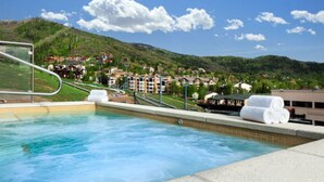 A swimming pool with a view of a hillside town and a building with a green roof.
