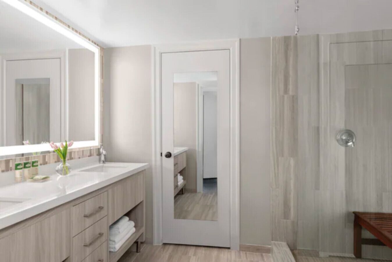 A modern bathroom with a large mirror, a sink, and a shower area.