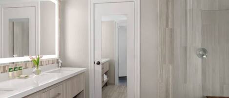 A modern bathroom with a large mirror, a sink, and a shower area.