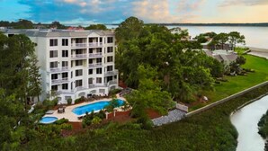 A multi-story hotel with a pool and a view of the water.
