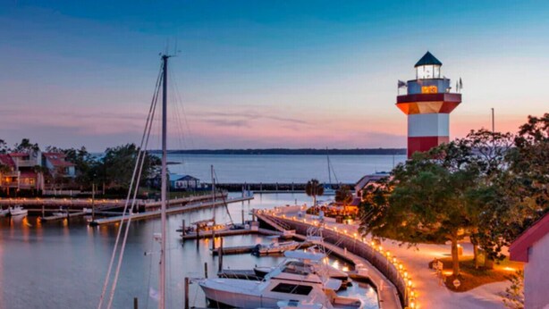 A marina with boats docked, a lighthouse, and a waterfront view.