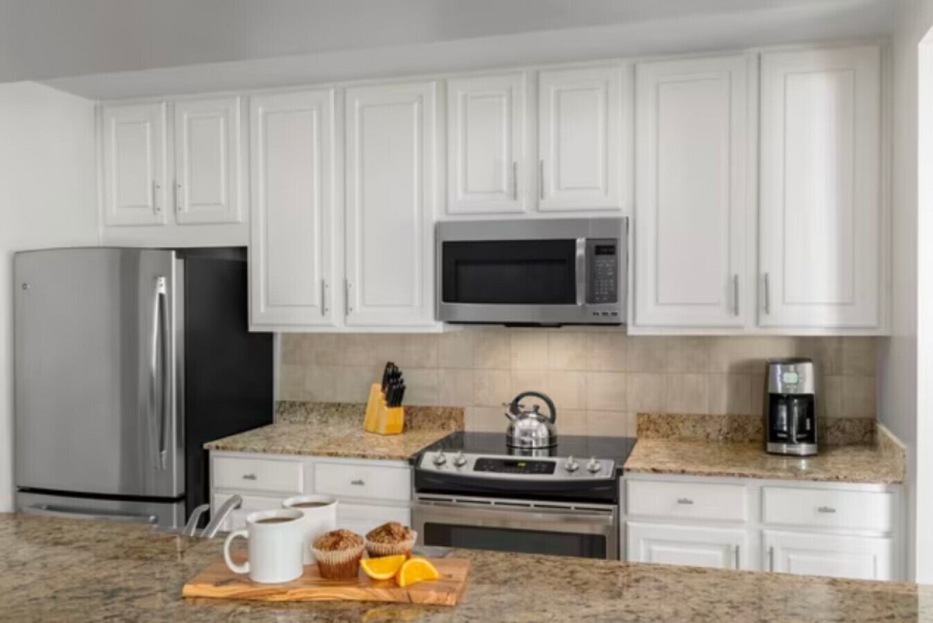A modern kitchen with white cabinets, stainless steel appliances, and granite countertops.