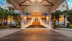 A hotel entrance with a grand staircase, a covered walkway, and a brick-paved area.