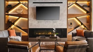 Ein modernes Wohnzimmer mit Kamin, zwei Sofas und einem an der Wand befestigten Flachbildfernseher.