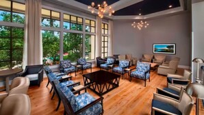 A spacious living room with a large window, a chandelier, and multiple seating areas.